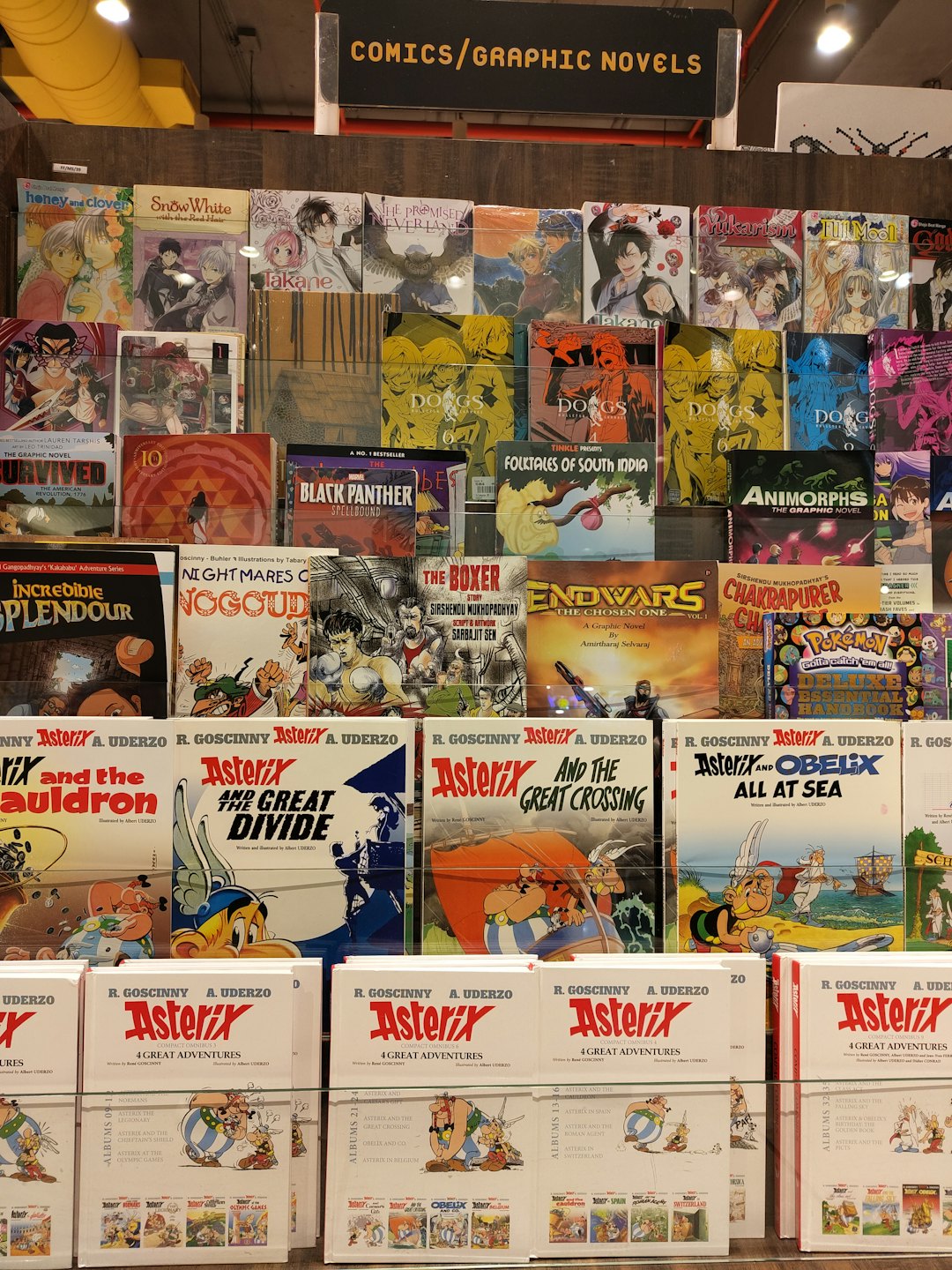 Comic books and graphic novels displayed on shelves in a bookstore.