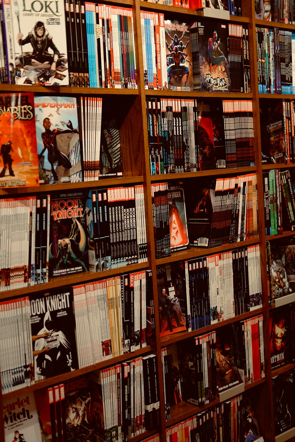 Wooden bookshelf filled with various comic books and graphic novels.